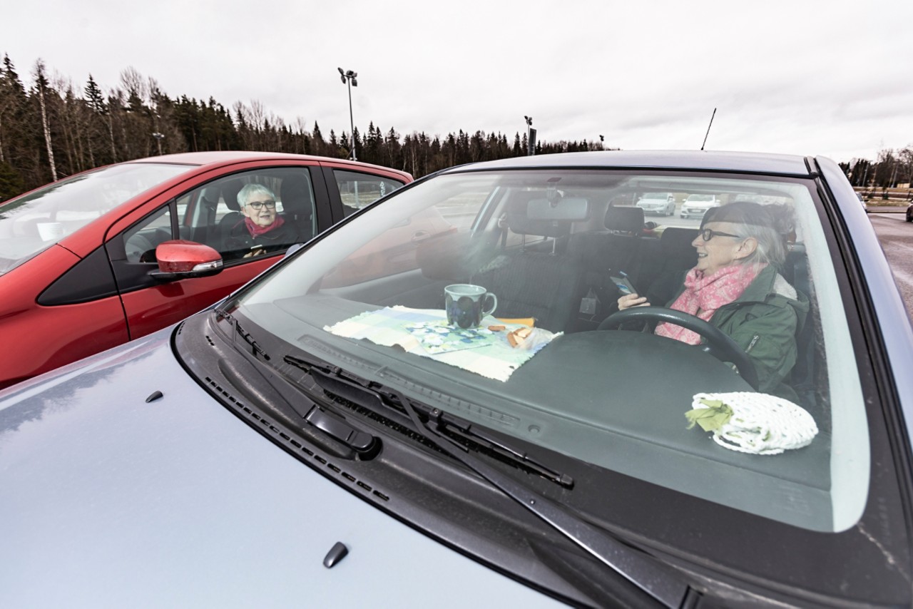 Toyota-kuskit Leila Valtonen ja Marjukka Leiwo keksivät keinon tavata toisiaan koronapandemian aikana. He kahvittelevat autojensa suojissa.
